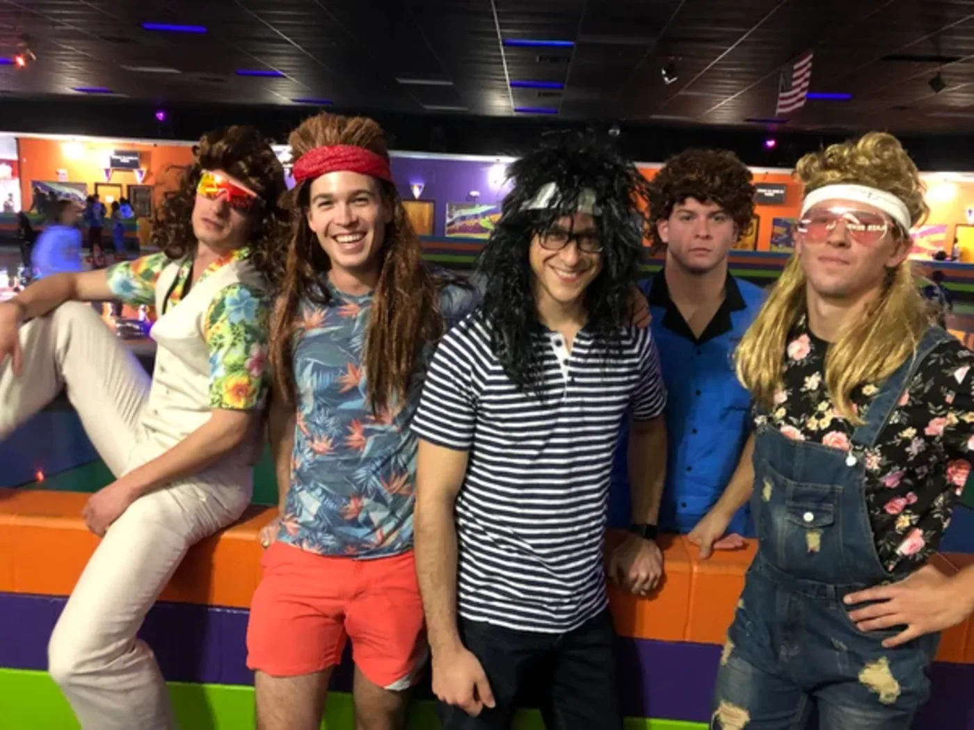 A lineup of friends in mullets and bright eighties outfits at a bar