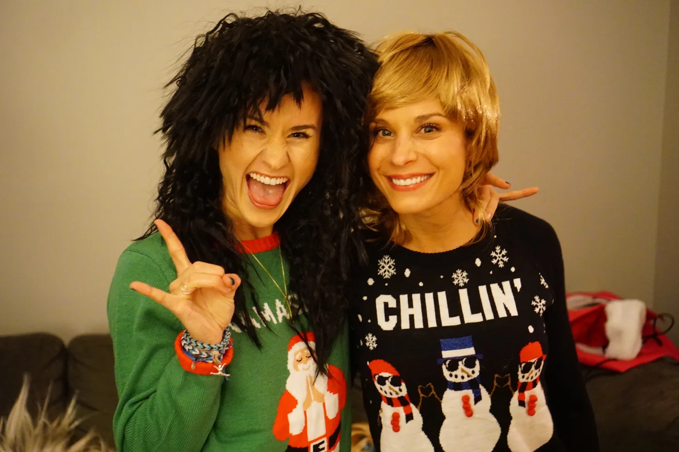 Two friends in mullets and holiday sweaters holding drinks