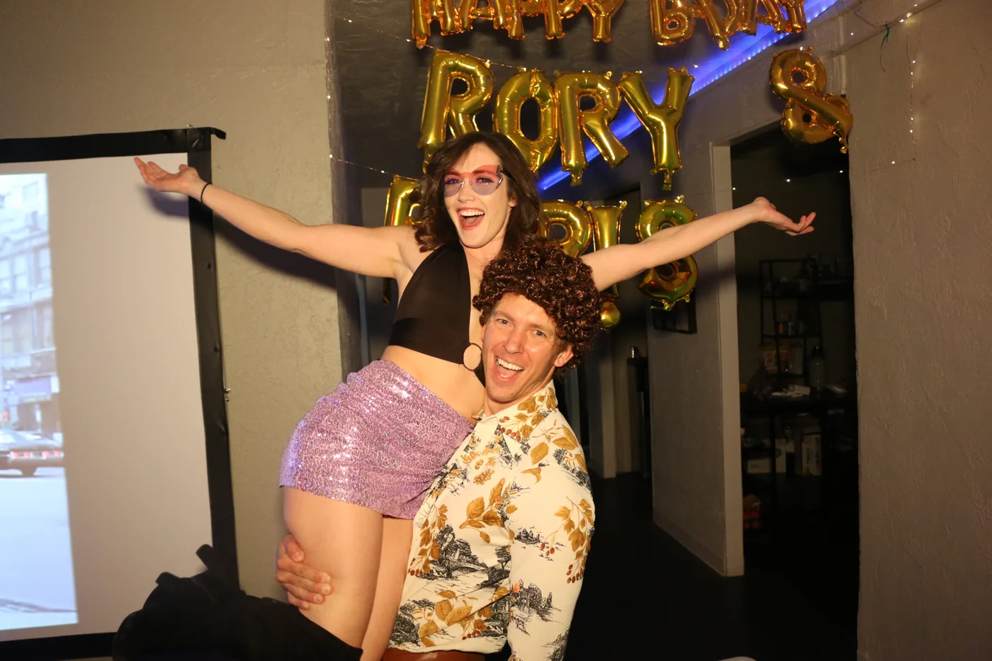 A guest in a mullet posing under a Happy Birthday banner