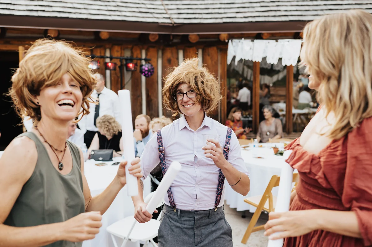 Three guests in mullets laughing together, mid-conversation, peak reception.