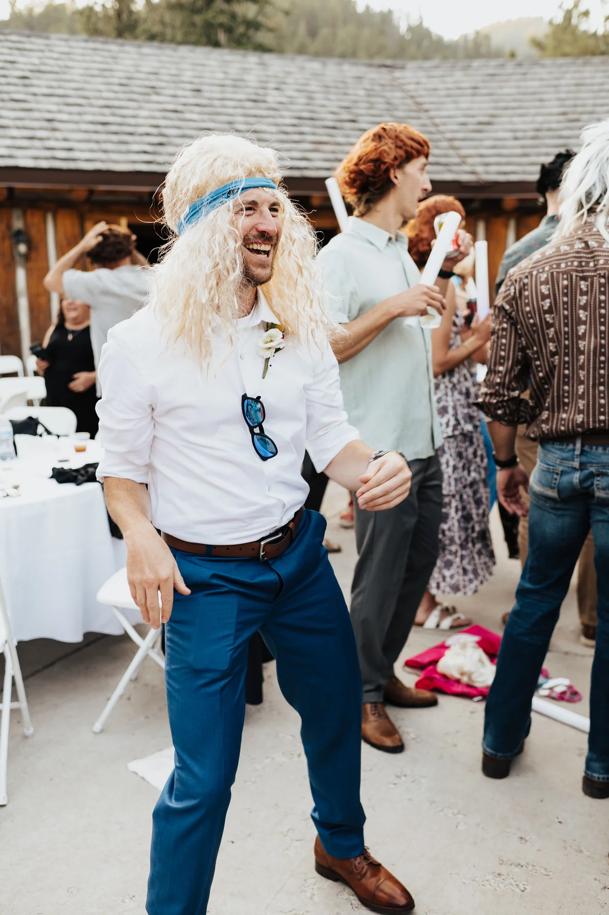 Groomsman in a long blonde mullet doing a full rockstar pose.