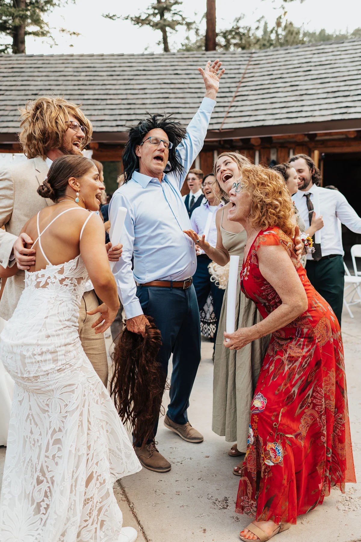 Five guests reacting around the dad in a black mullet, hand raised.